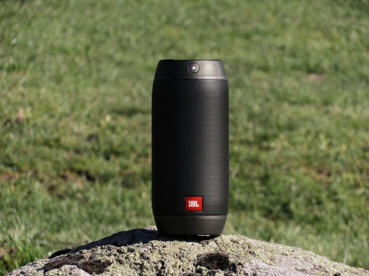 a black speaker sitting on top of a rock