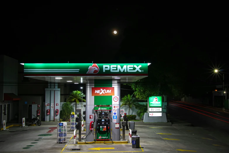 a gas station at night time with green lights