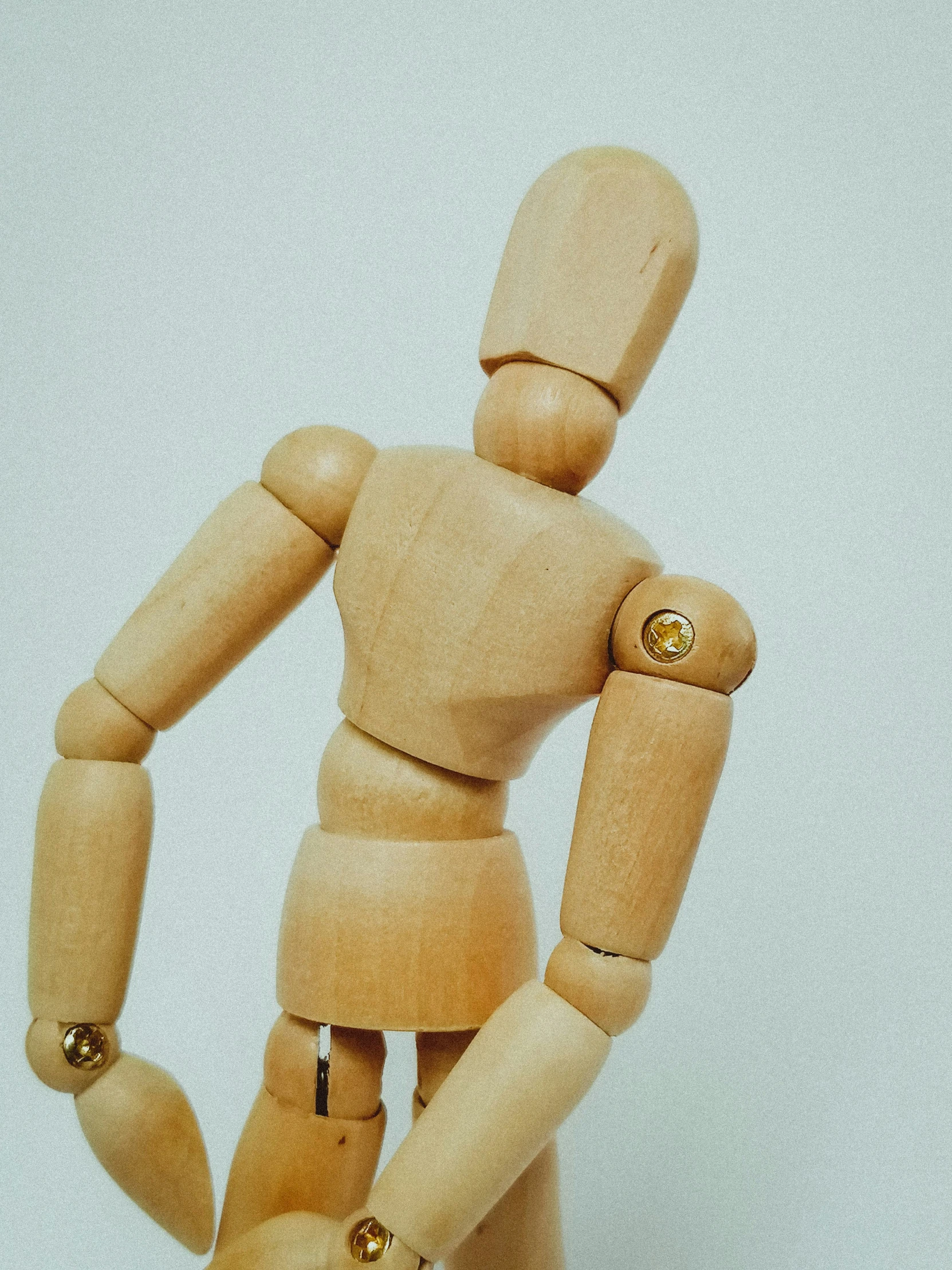 wooden mannequin with golden ons wearing a hat