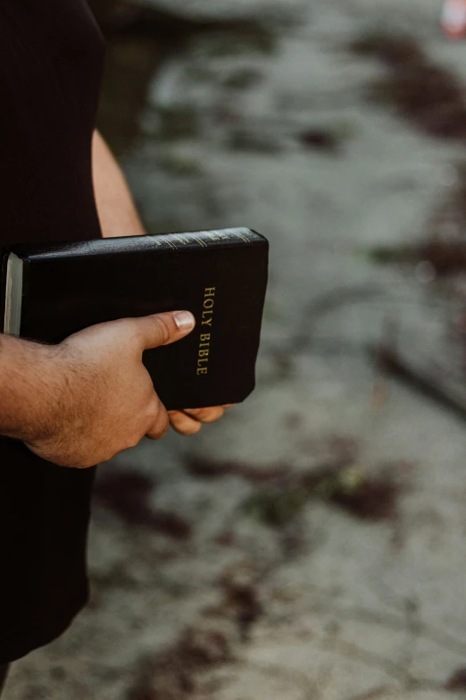 a man holding a bible in one hand and wearing a celet