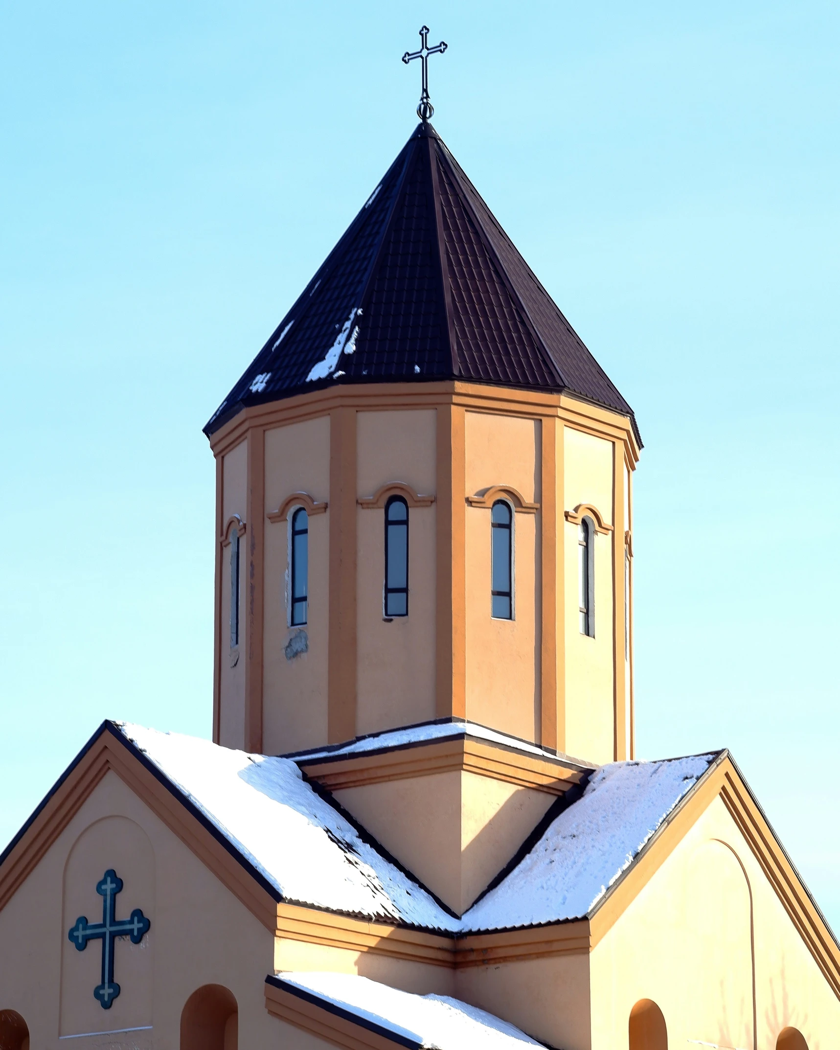 the tall building has a steeple and a cross at the top