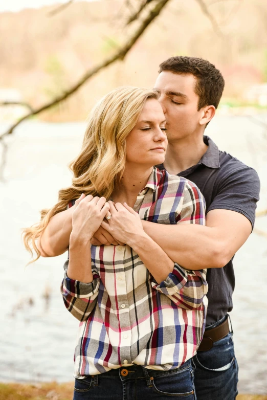 a beautiful blonde woman with long hair hugging a man who has her hands around him