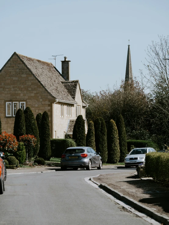 two cars driving down a quiet street next to houses