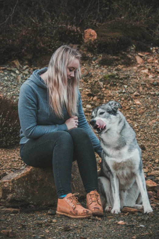 a girl sits with her dog next to some rocky terrain