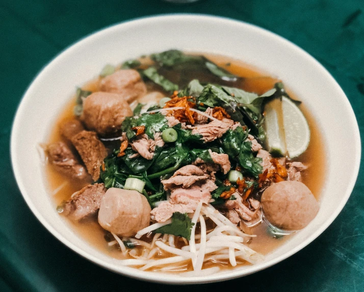 this is a white bowl filled with meat, vegetable and noodles