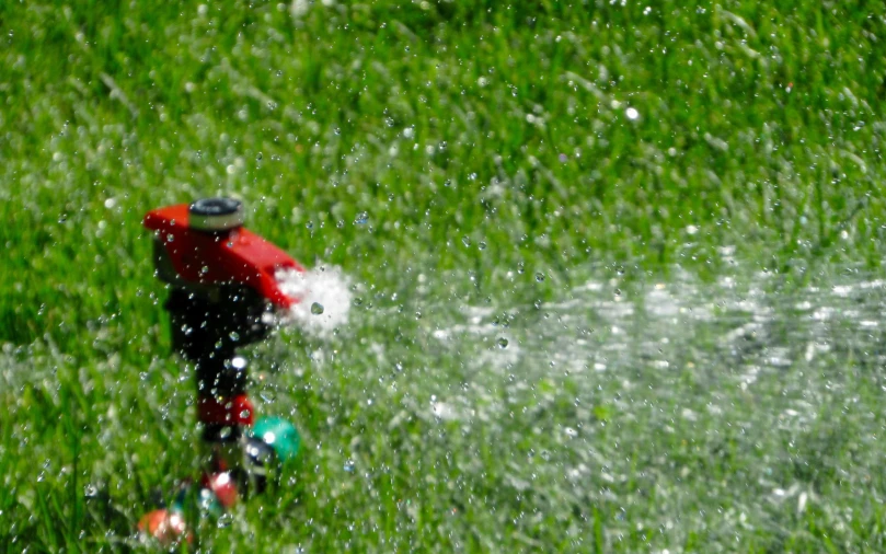 a man in red and black jacket holding hose spraying water