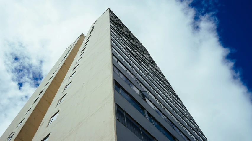 a tall building with lots of windows under a cloudy blue sky