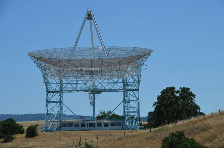 a large metal structure stands near some trees