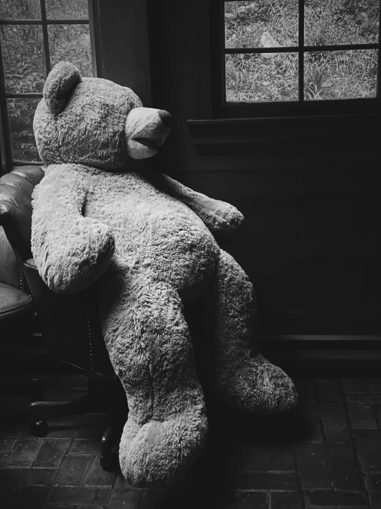 the large teddy bear sits by the window in the room