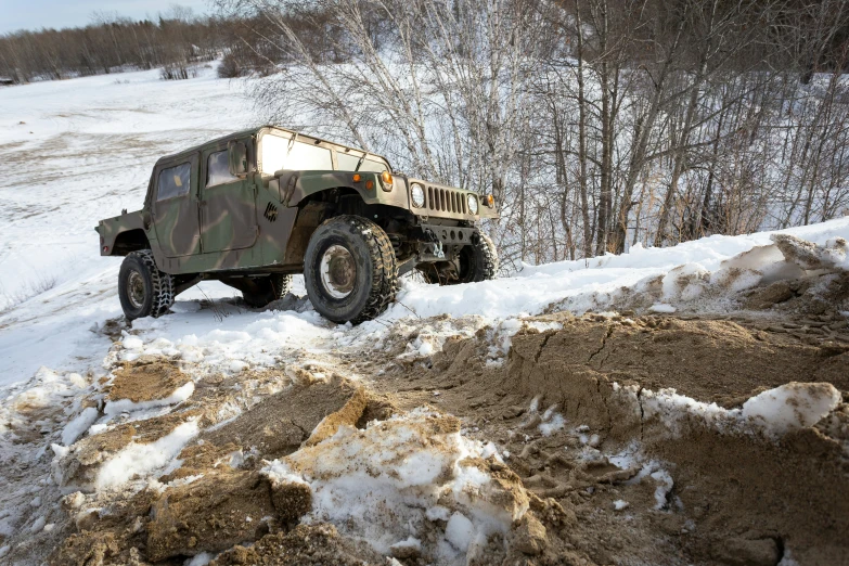 a green and white military vehicle driving down a snowy road