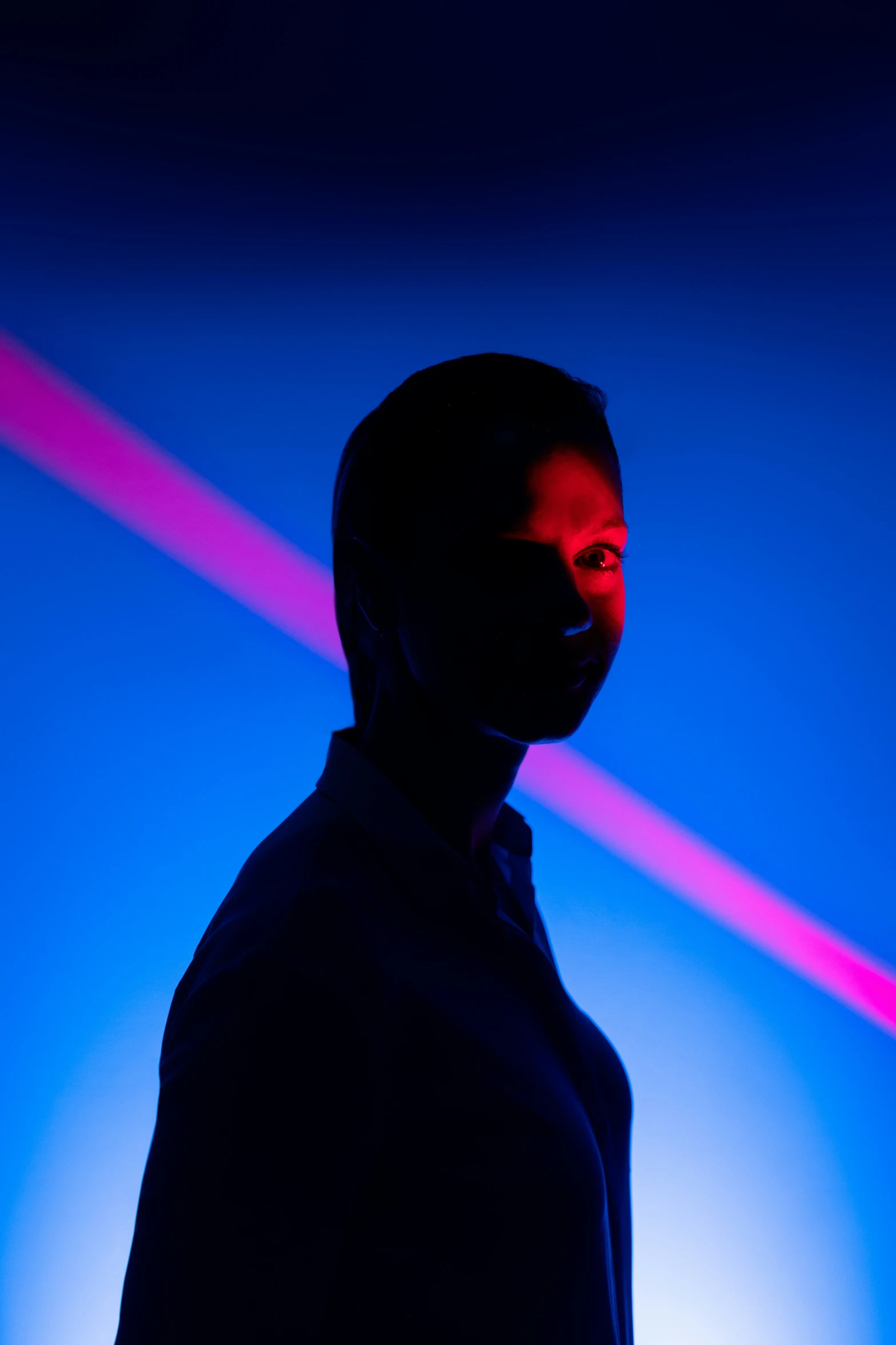 a silhouette against a colored wall wearing a face mask