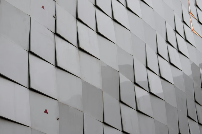 an abstract wall of white tiles with red triangulars