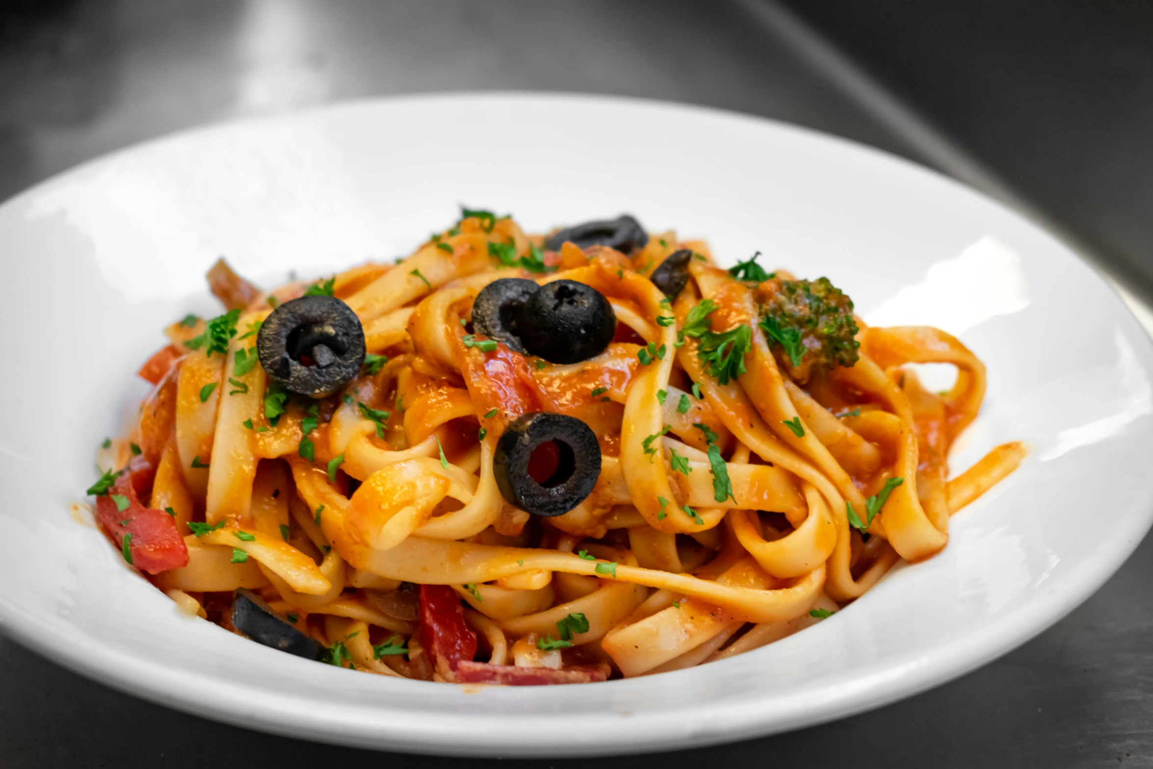 a close up of a plate of pasta with olives