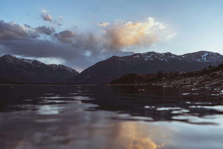 a sail boat on the lake in front of some mountains