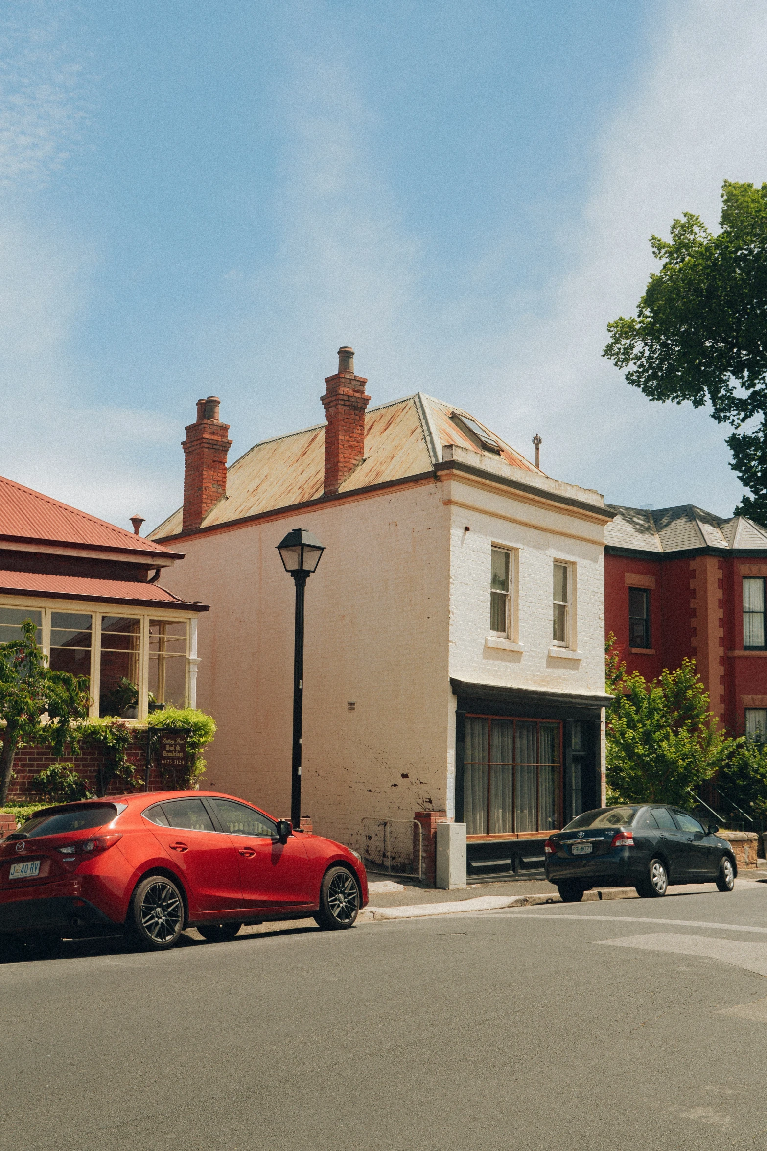 two cars are parked on the curb beside a small house