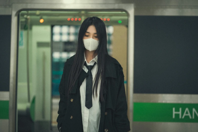 a woman in black jacket and white face mask at subway platform