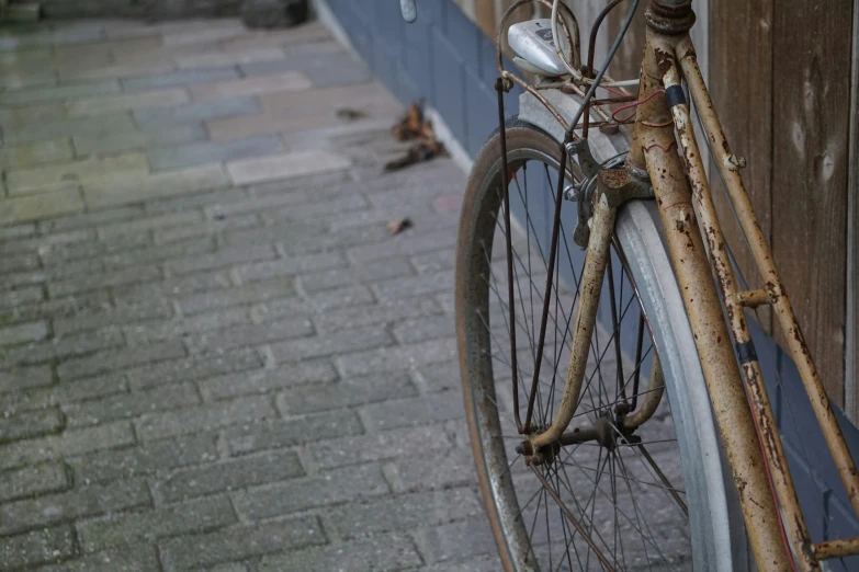 an old bicycle leans on a wall by the sidewalk