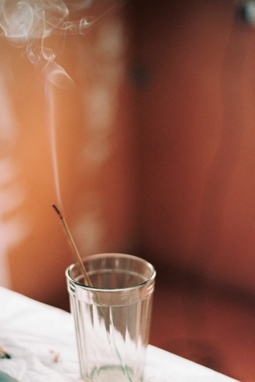 smoke rises from the sticks that were sticking out of a cup of water