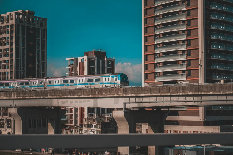 a train passing over a bridge with tall buildings in the background