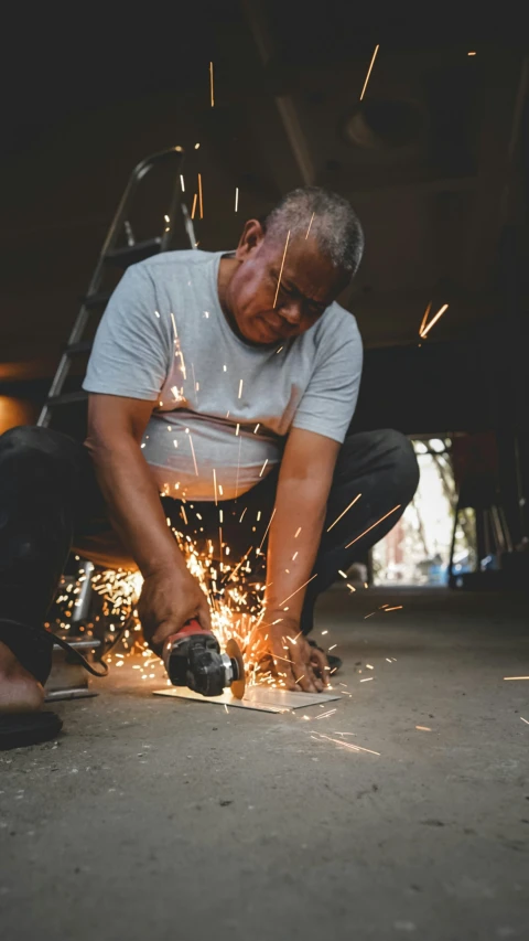 a man in grey shirt grinding metal