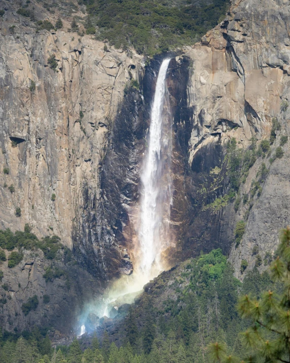 a large waterfall flows from a mountain side into the water