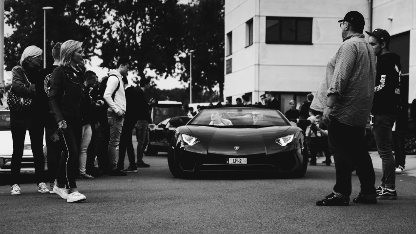 a man is standing in front of his car and looking at the car