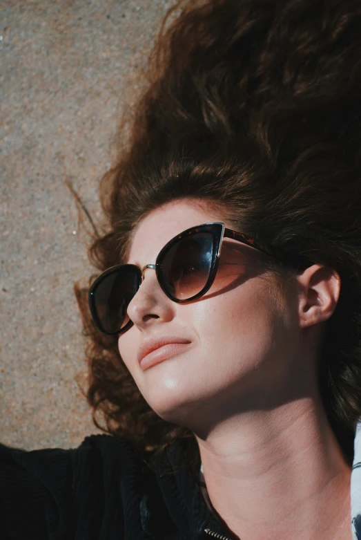 a woman with sun glasses is resting on a ground