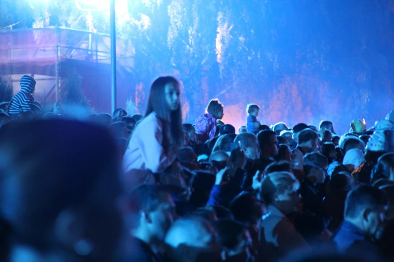 a crowd watches as a man standing on a stage