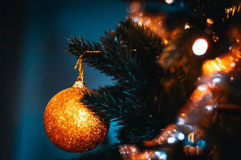 a gold ornament hangs from a christmas tree