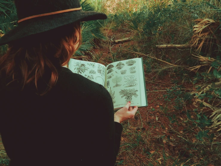 woman standing outdoors, reading the book in the grass