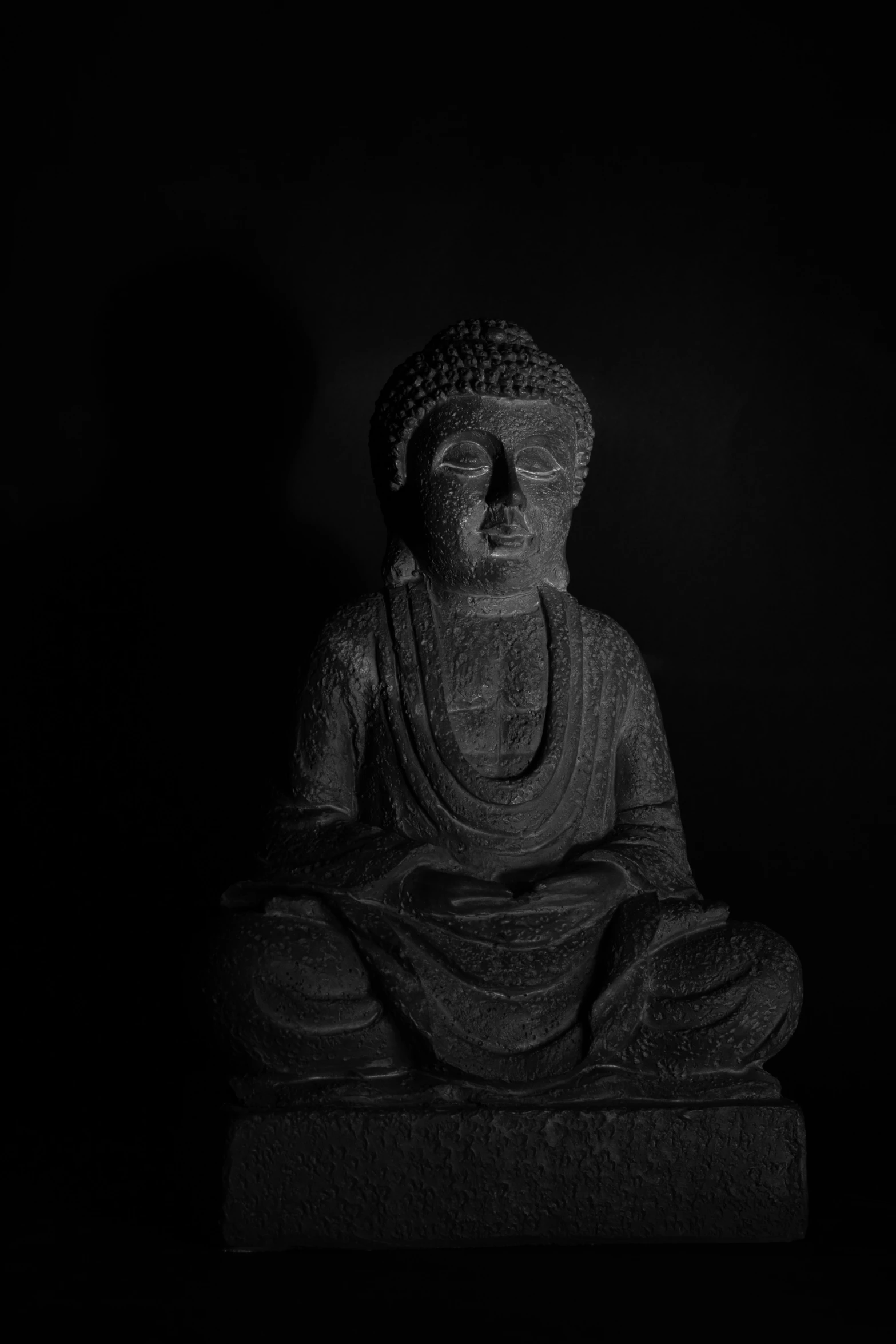 a buddha statue sitting in the dark with its eyes closed