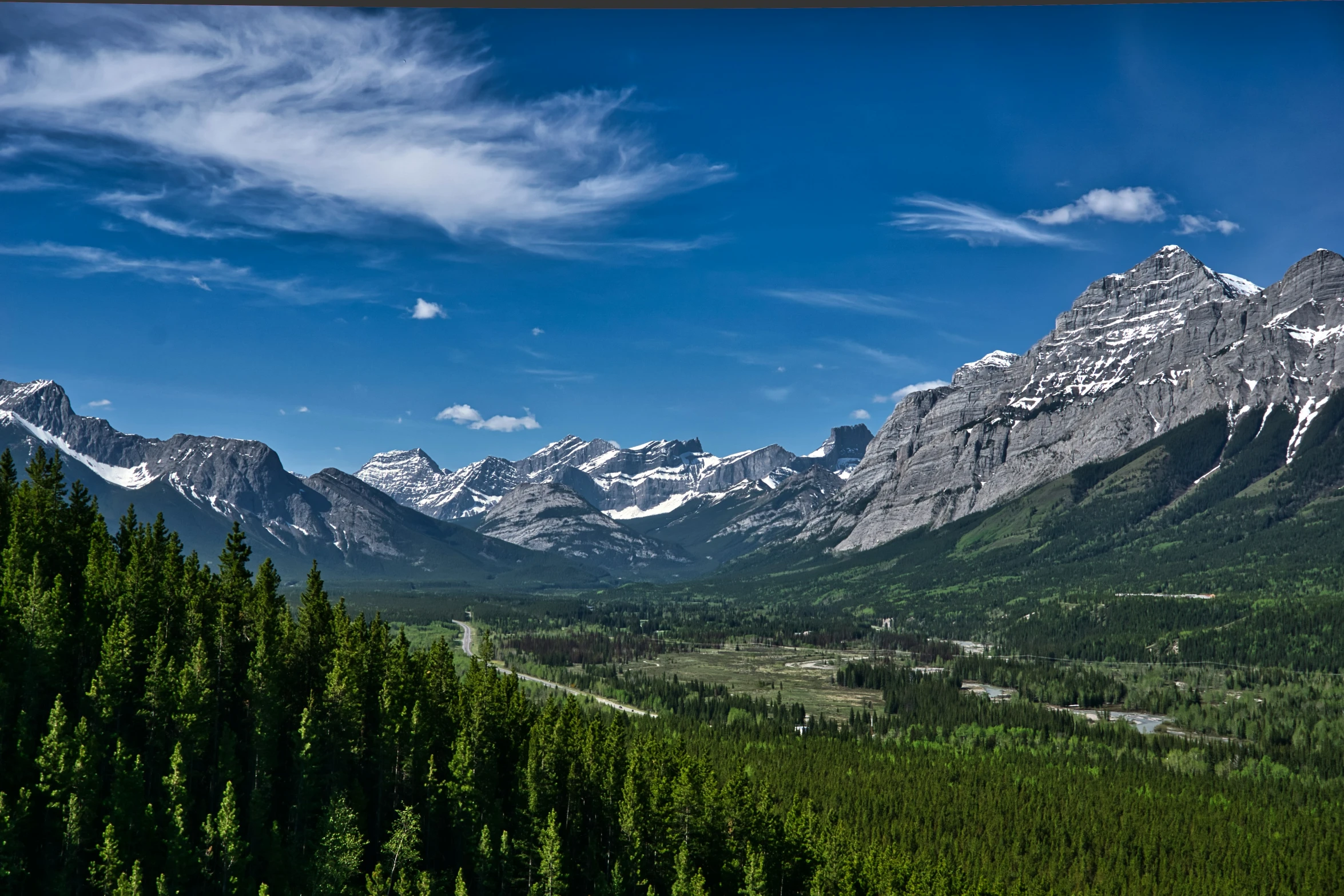 mountains and trees are seen against a blue sky