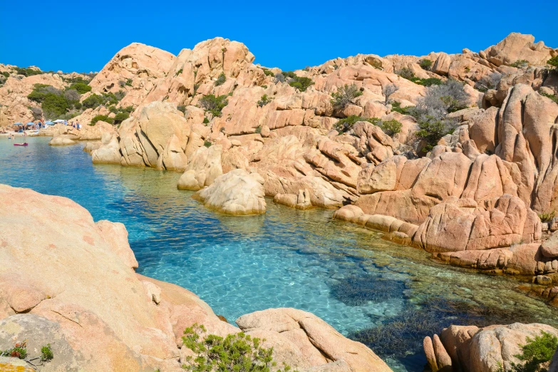 clear blue water surrounded by large boulders and grass