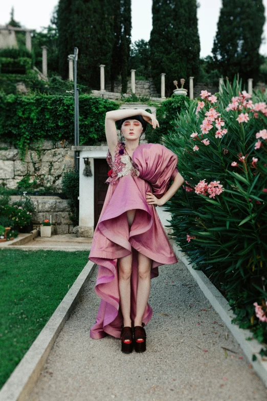 a young woman poses in front of a flowered garden