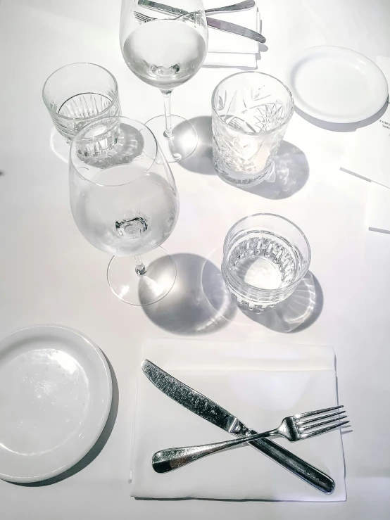 a table setting with clear glasses, knives and plates