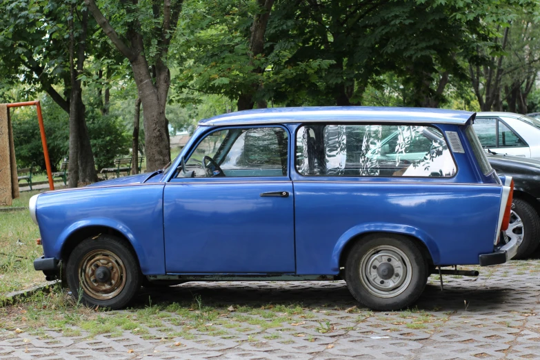 an old blue car parked on a street