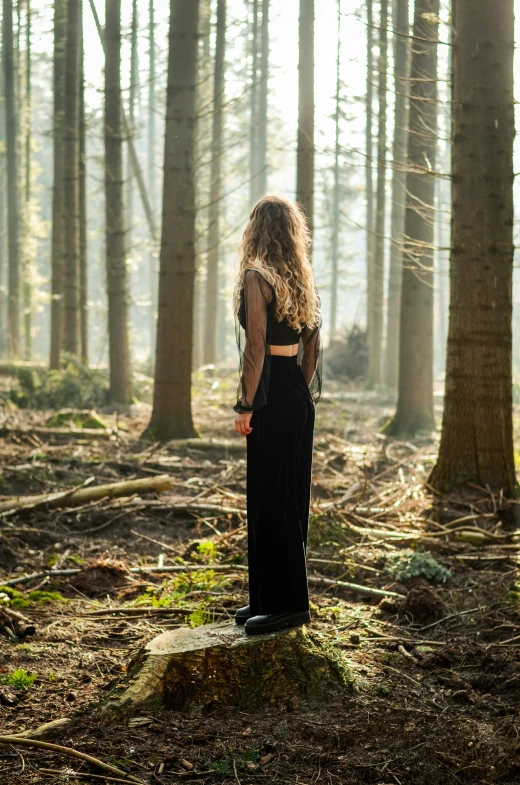 a woman in the middle of a forest with her hands on her hips