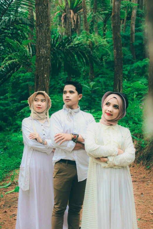 two people standing in front of trees in the woods