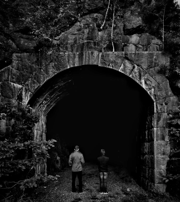 two men standing at the end of a tunnel