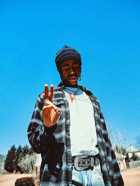 a man with a hat on is holding up a peace sign