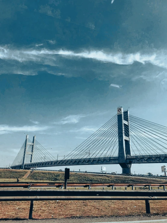 a bridge over water and under a cloudy blue sky