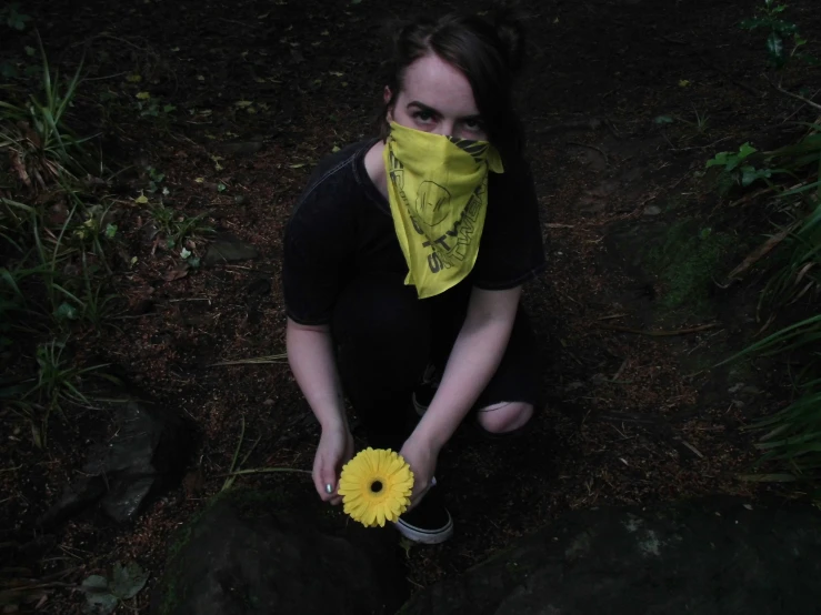 a person sits in the woods with a flower