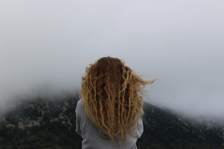 a woman with long dreadlocks standing on top of a hill