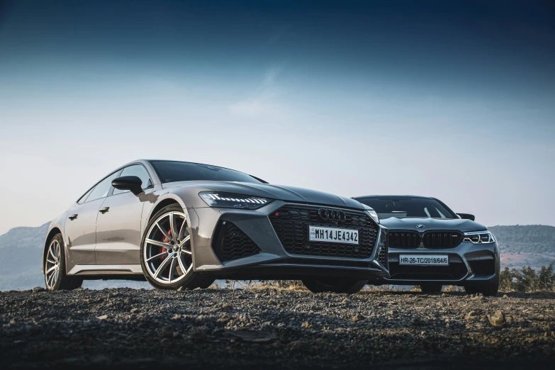 two silver cars parked on top of a dirt field