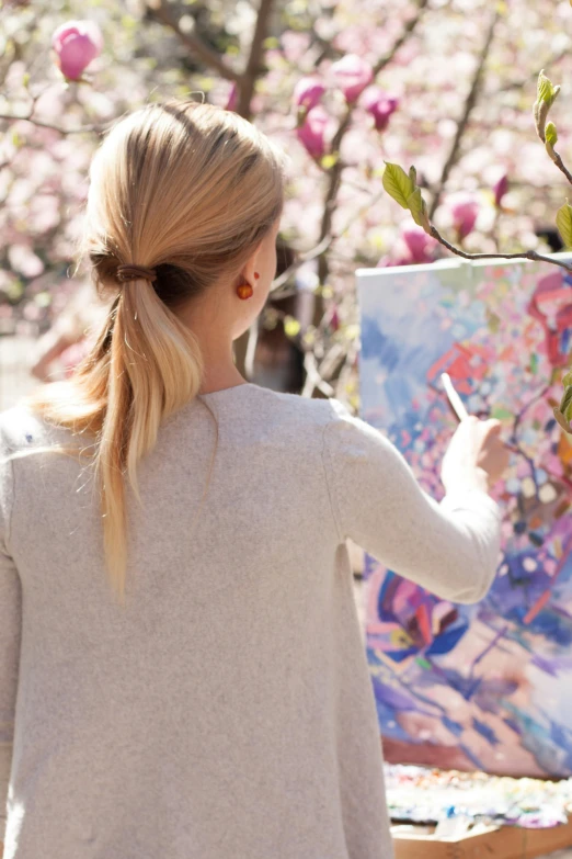 woman in a flowered park painting with a large palette