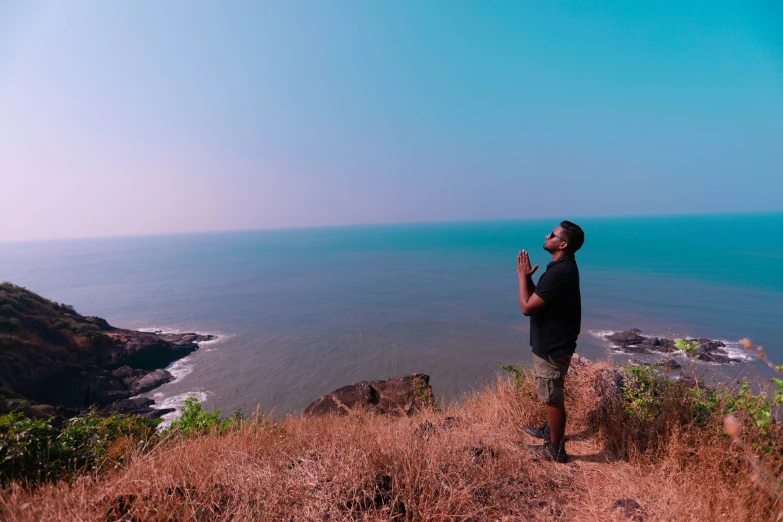 a man holding a cellphone while standing on top of a cliff