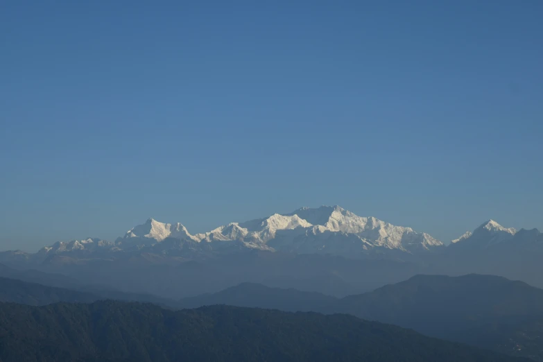 the white snow capped mountains rise above a deep blue sky