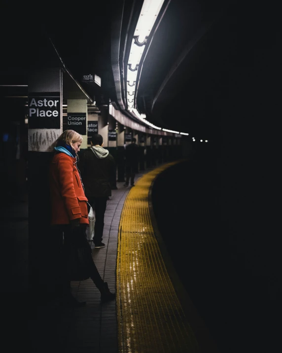 there is a man standing by the platform waiting for his train