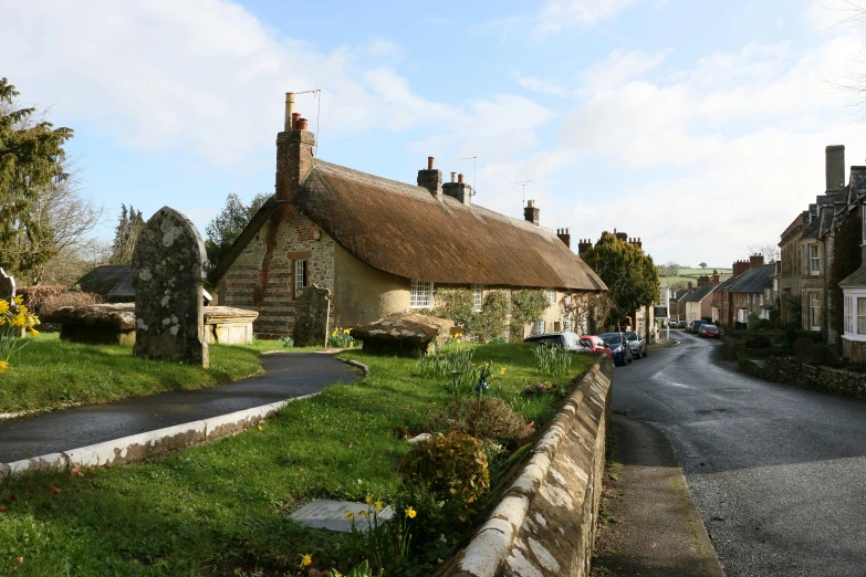 a stone cottage with a thatched roof in the village