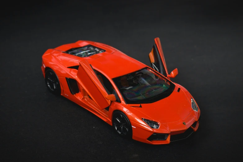 an orange toy car sitting on a black surface